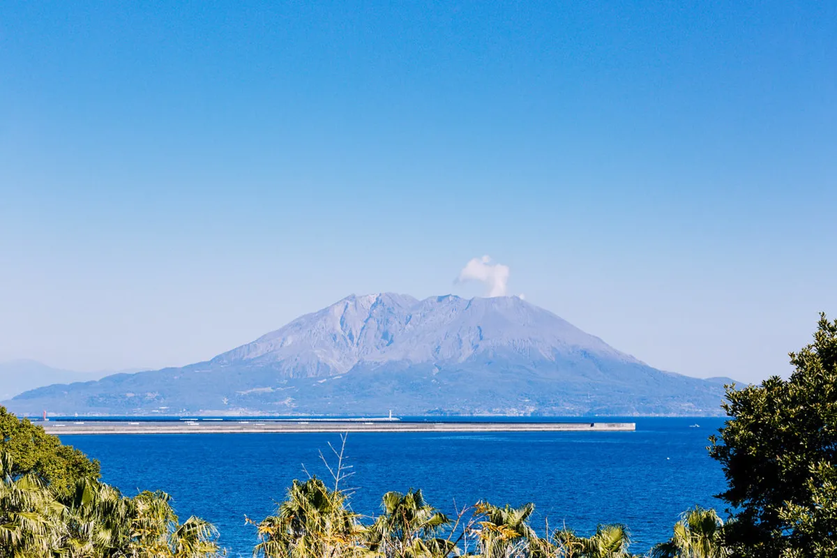 Sakurajima volcano active with plume of ash rising above Kagoshima Bay viewed from the city, Japan