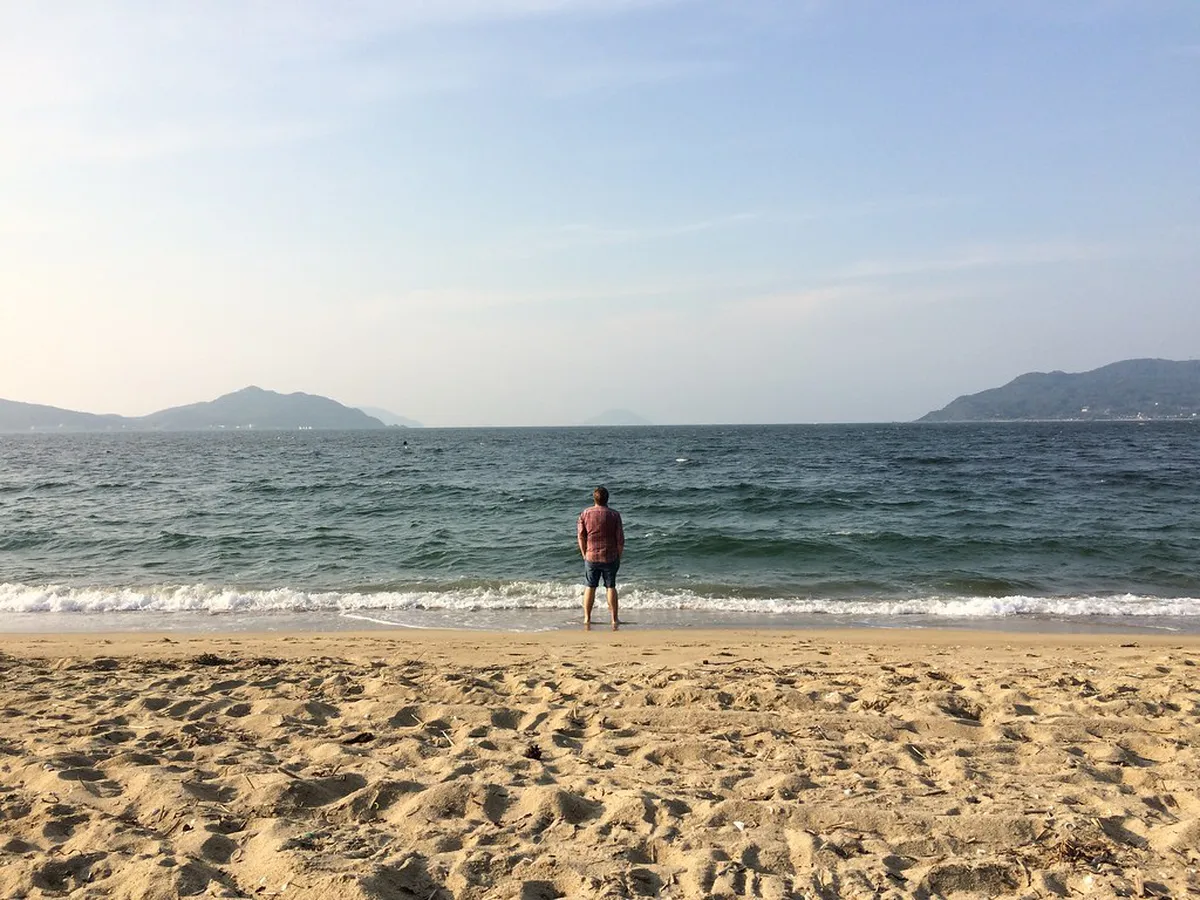 Sandy beach on the Fukuoka coastline with gentle waves and clear skies typical of summer along the Sea of Japan