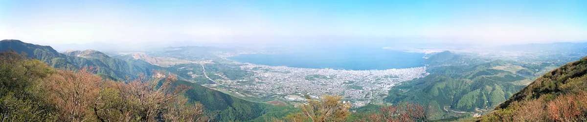 Beppu Bay in Japan viewed from the hills — turquoise Pacific waters stretching wide with the volcanic city skyline and rising steam below