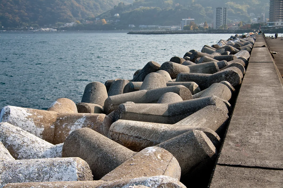 Myoban onsen district in Beppu, Japan — thatched-roof huts used for sulfur harvesting line the hillside above the hot spring facilities