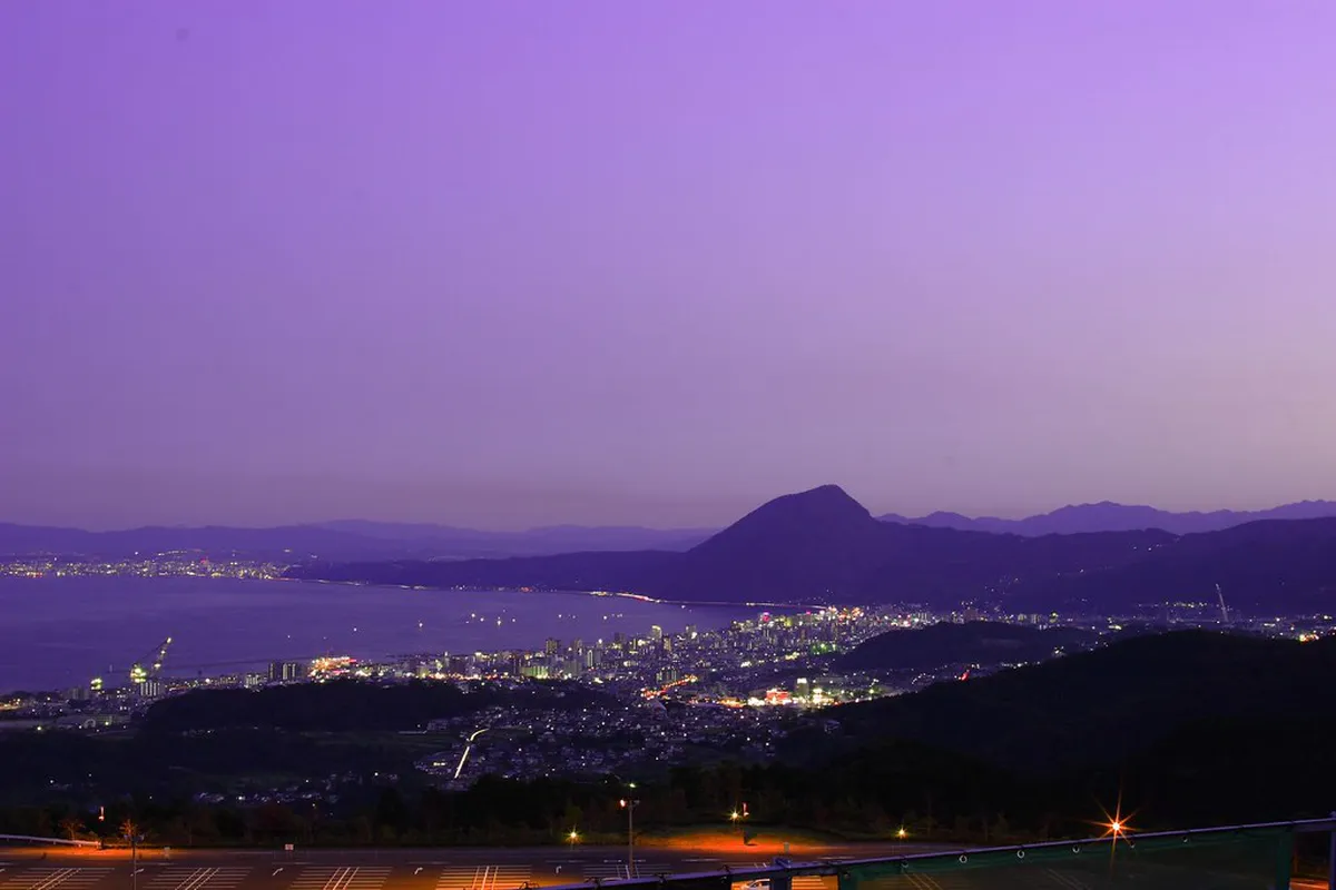 Beppu bay night view in Japan — city lights and geothermal steam reflecting over the dark water during the December winter illumination season