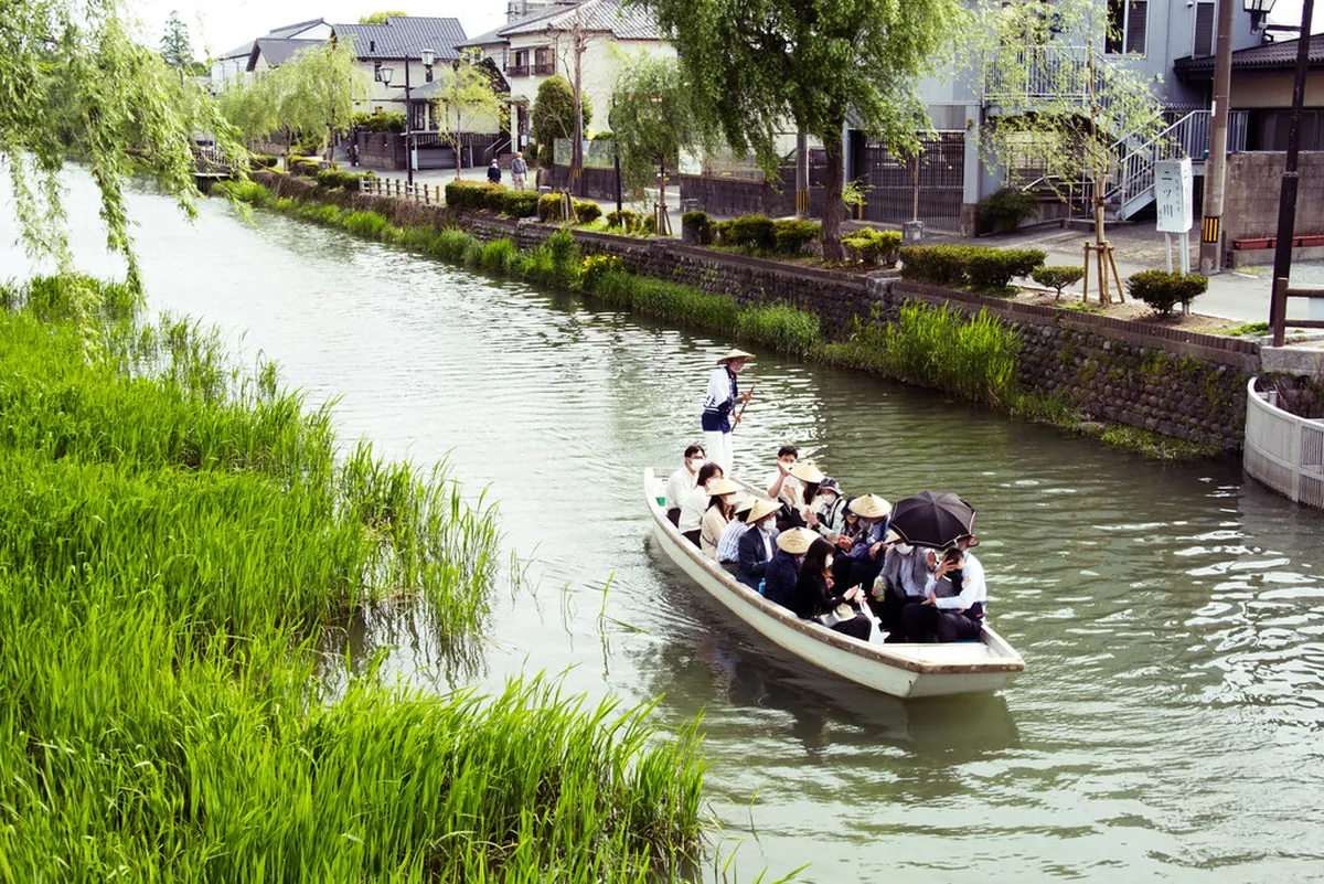 Traditional wooden boat gliding along the scenic Yanagawa canals with willow trees lining the banks, Japan