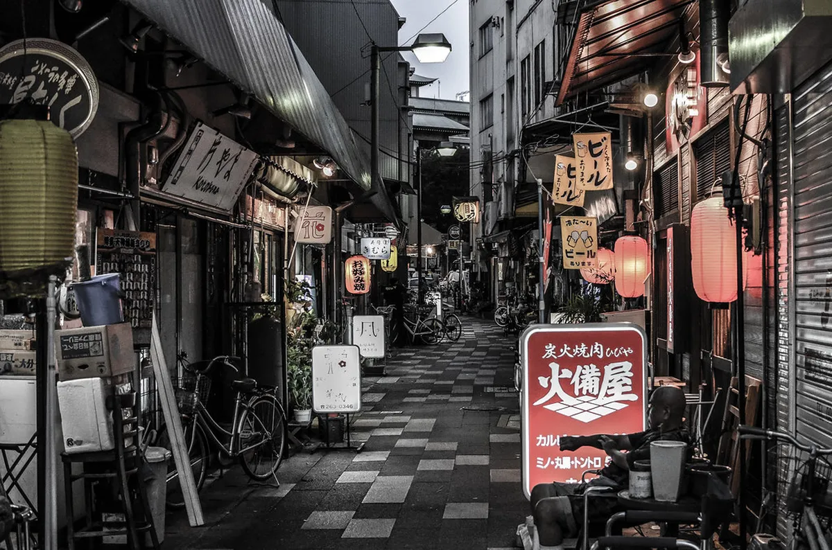 Diners enjoying a meal inside a warm and busy Fukuoka izakaya restaurant with Japanese food and drinks, Japan