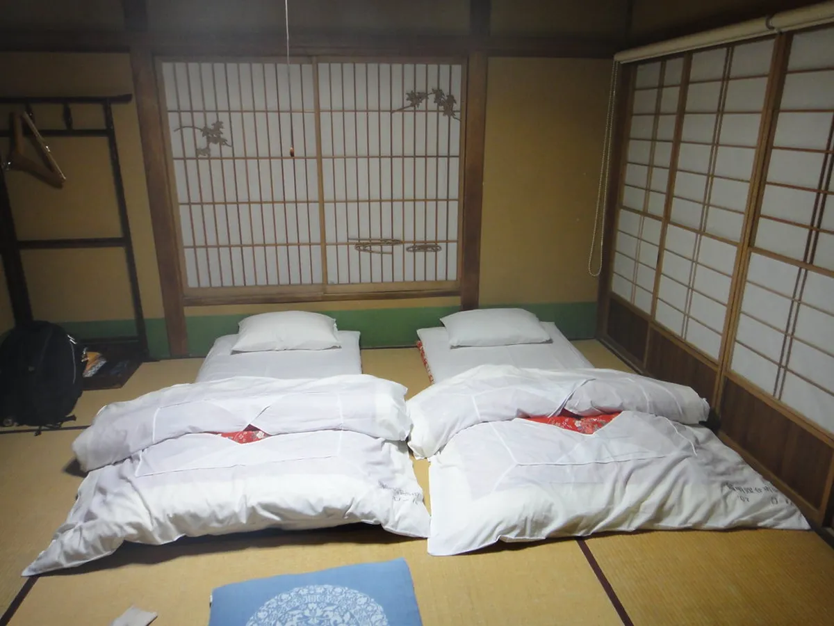 Traditional Japanese inn room with tatami flooring and futon bedding