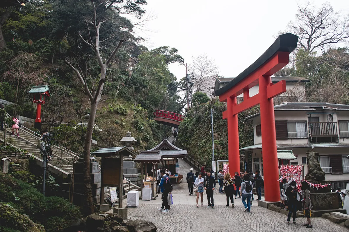 Enoshima island shrine entrance with torii gate and visitors walking along the causeway in Kamakura Japan