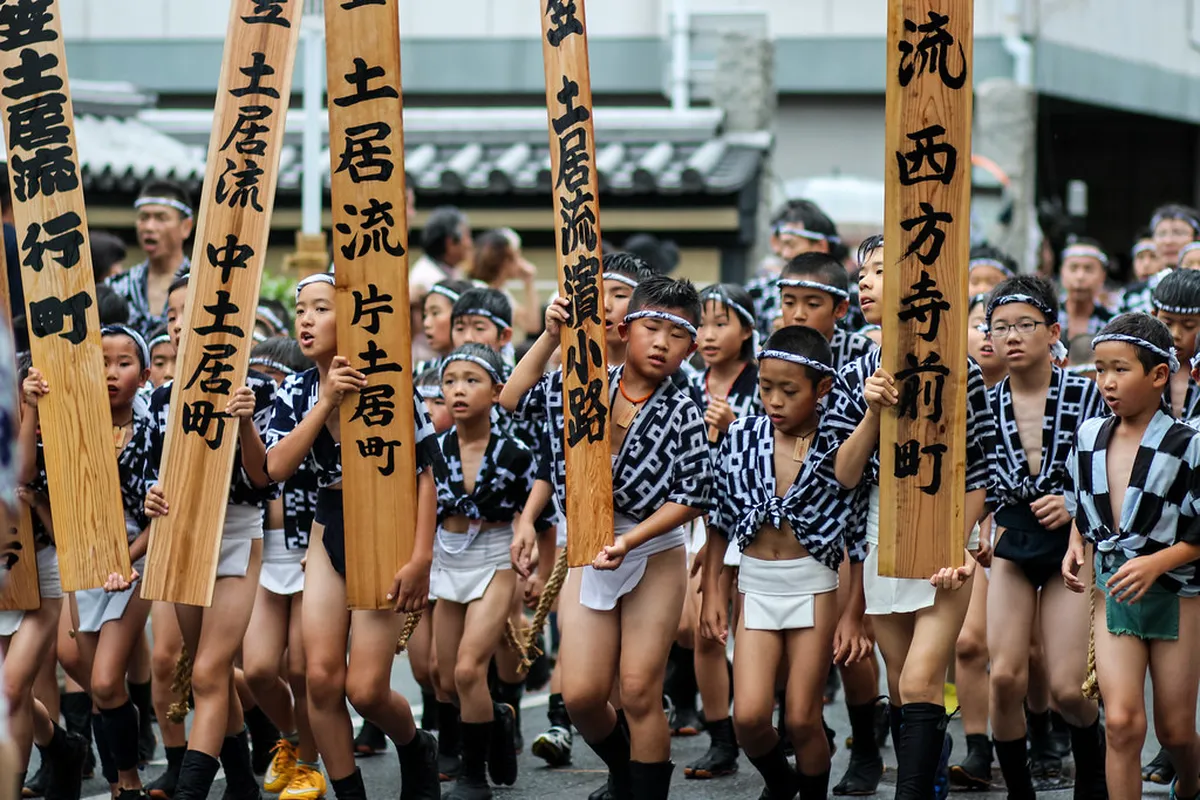 Men in traditional happi coats carrying a heavy racing float through the streets during Hakata Gion Yamakasa festival in Fukuoka Japan