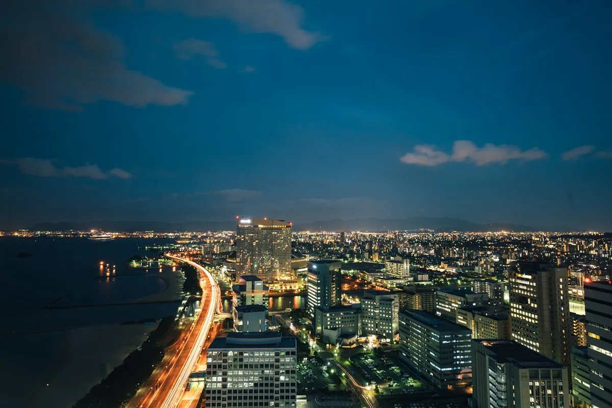 Fukuoka city skyline at dusk viewed from an elevated vantage point showing the urban landscape and Hakata Bay