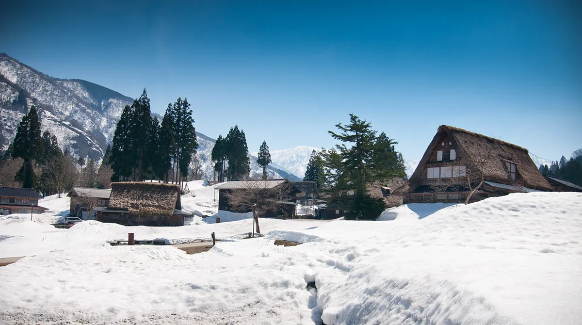 Snow-covered gassho-zukuri farmhouses in Gokayama during winter, the fields blanketed in deep snow creating the iconic UNESCO heritage scene