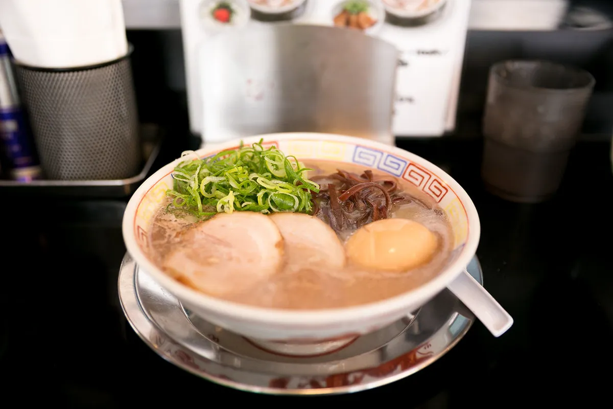 A bowl of tonkotsu ramen with rich cloudy broth and thin noodles at a Hakata ramen restaurant in Fukuoka, Japan
