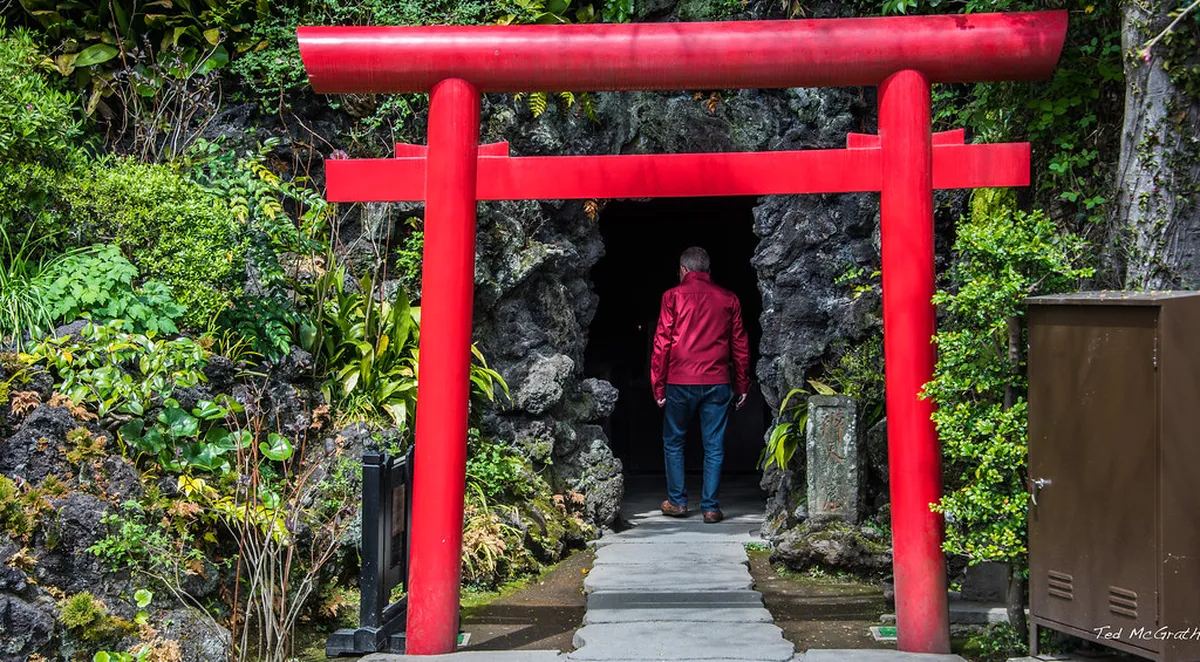 The dimly lit Benten-kutsu cave at Hase-dera temple in Kamakura, Japan, with carved stone statues and candles lining the low tunnel walls