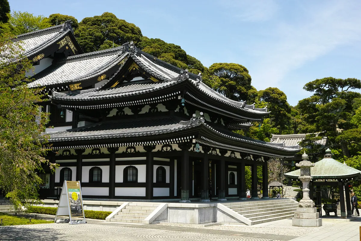 Hasedera temple entrance in Kamakura with traditional stone steps and wooden structures set among lush green hillside gardens