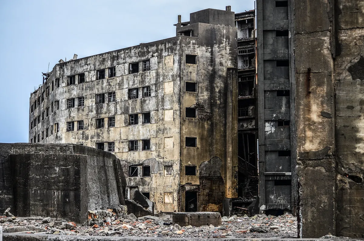 Crumbling apartment blocks and overgrown ruins of the abandoned Hashima Island settlement near Nagasaki, Japan
