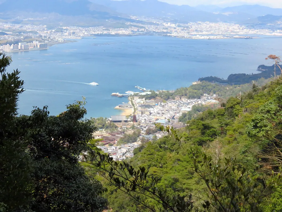 Hikers climbing the stone steps of Mt Misen trail on Miyajima Island with forest views in Japan