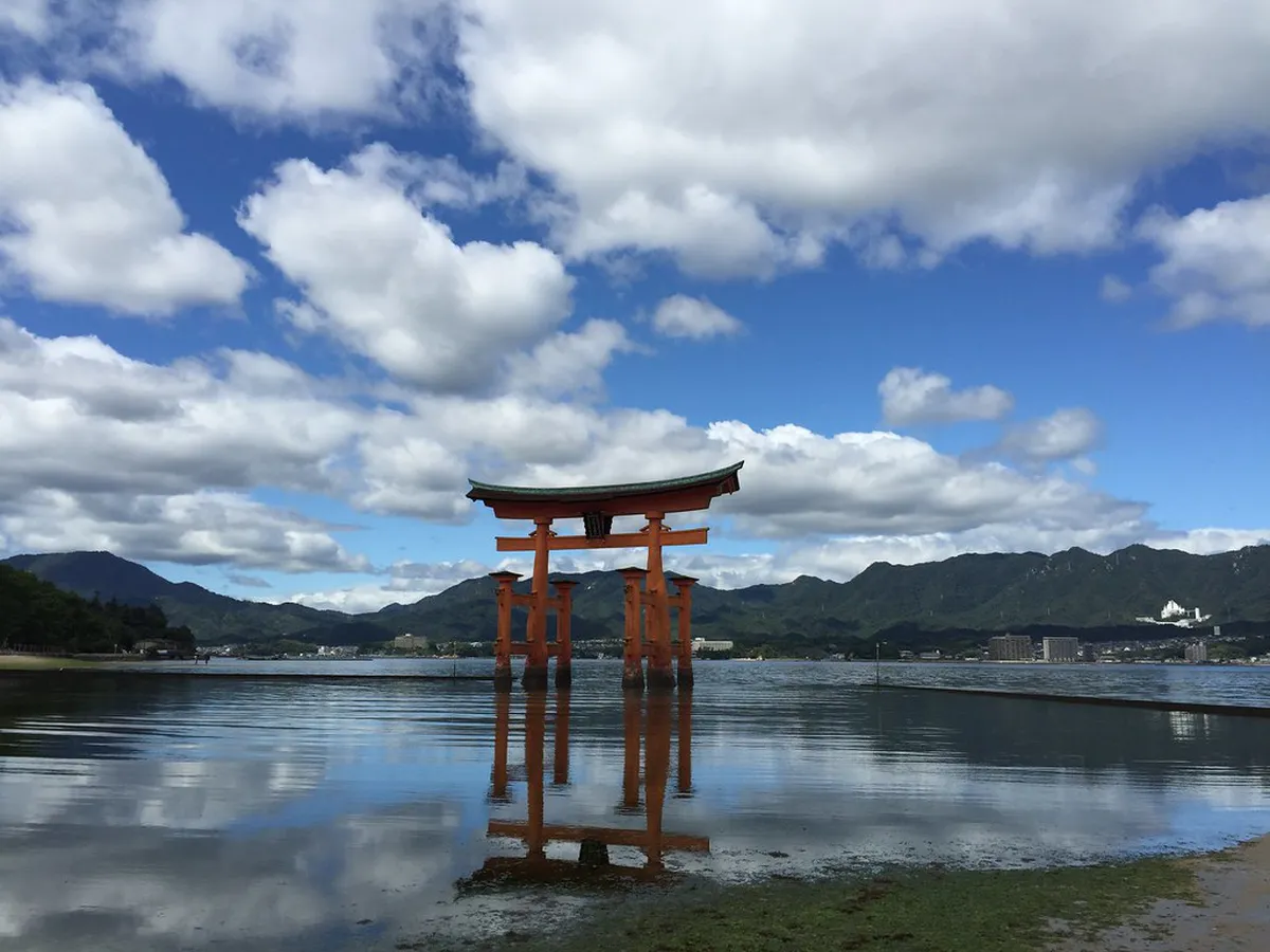 Miyajima Itsukushima Shrine vermilion pillars and floating torii gate over calm water in Hiroshima, Japan