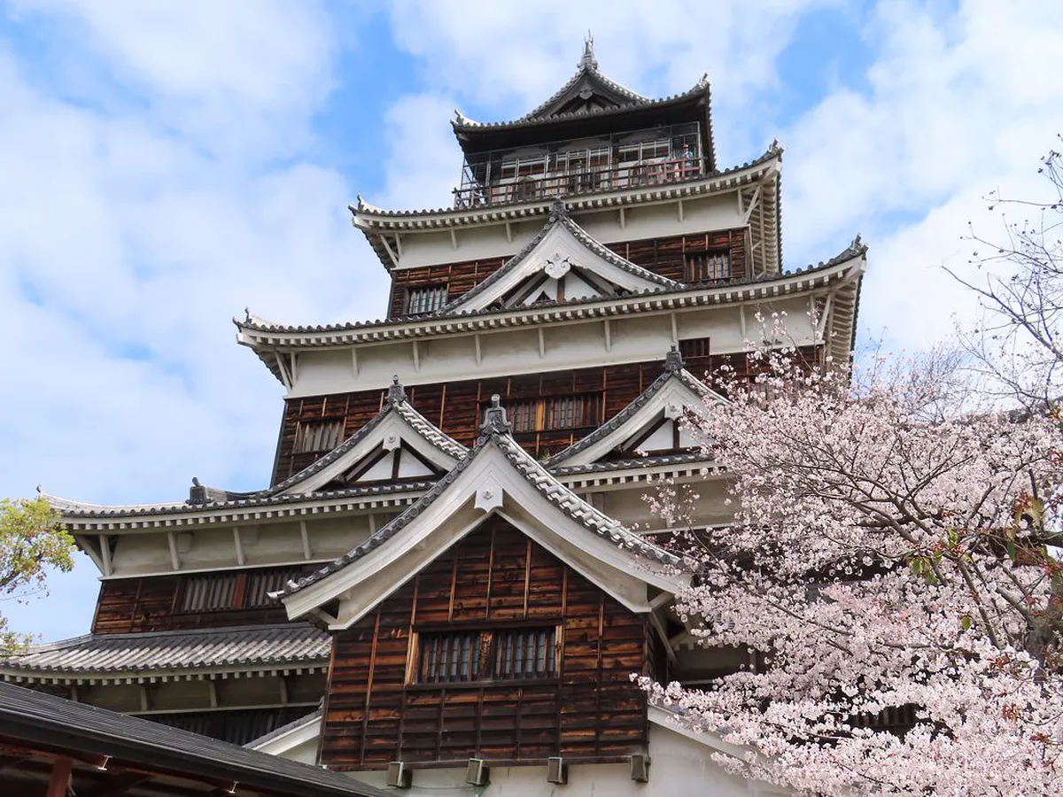 Hiroshima Castle five-story keep with traditional black wooden exterior rising above the moat in Japan