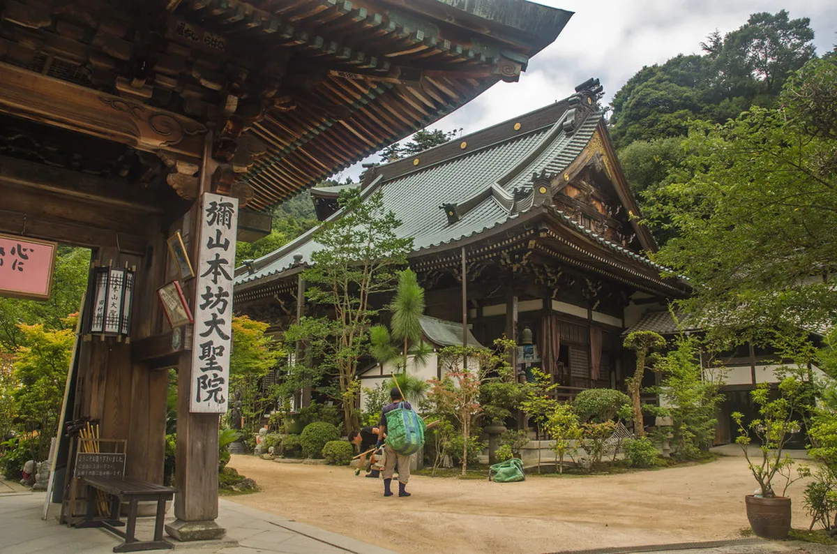 Miyajima Daisho-in Temple stone lanterns and Rakan statues lining the forested staircase on the island in Japan