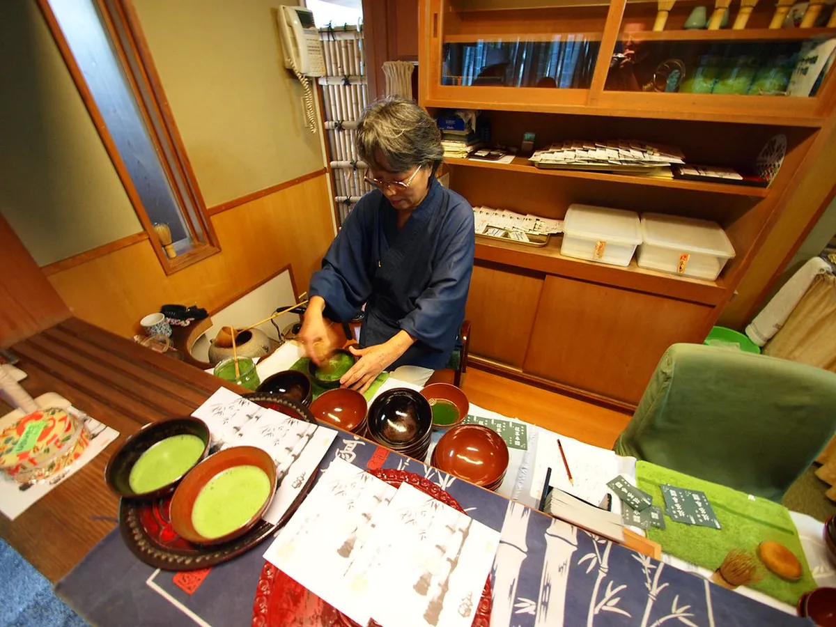 Matcha tea ceremony at Hokokuji Kamakura with a bowl of whisked green tea served on a tatami platform overlooking the bamboo grove