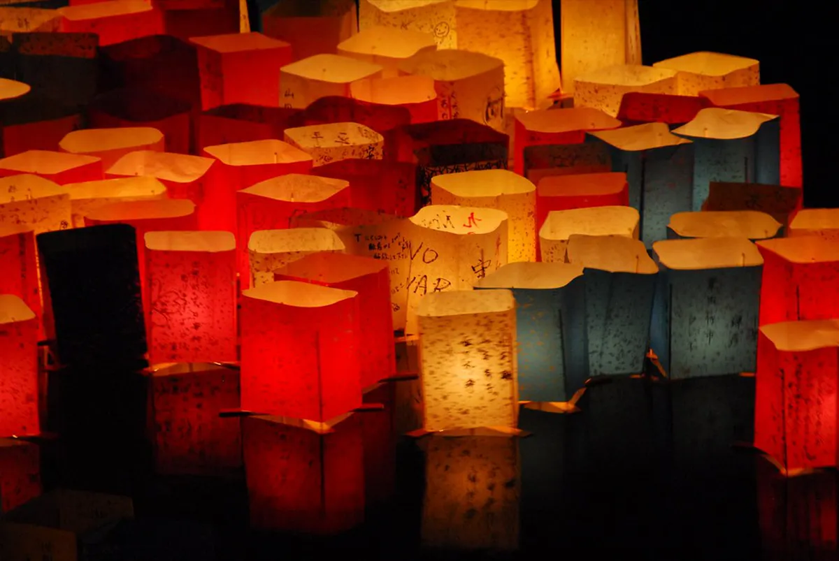 Paper lanterns floating on a river at night during a Japanese Toro Nagashi ceremony, glowing with candlelight
