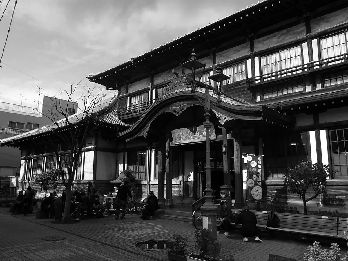 Attendant covering a bather with warm volcanic sand at a traditional Beppu sand bath onsen in Japan