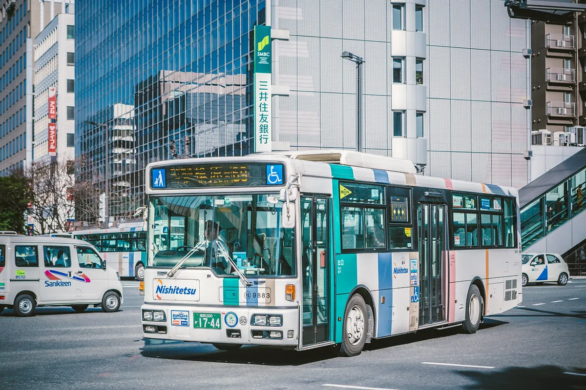 Nishitetsu bus on a Fukuoka city street, serving neighborhoods and attractions beyond the subway network, Japan