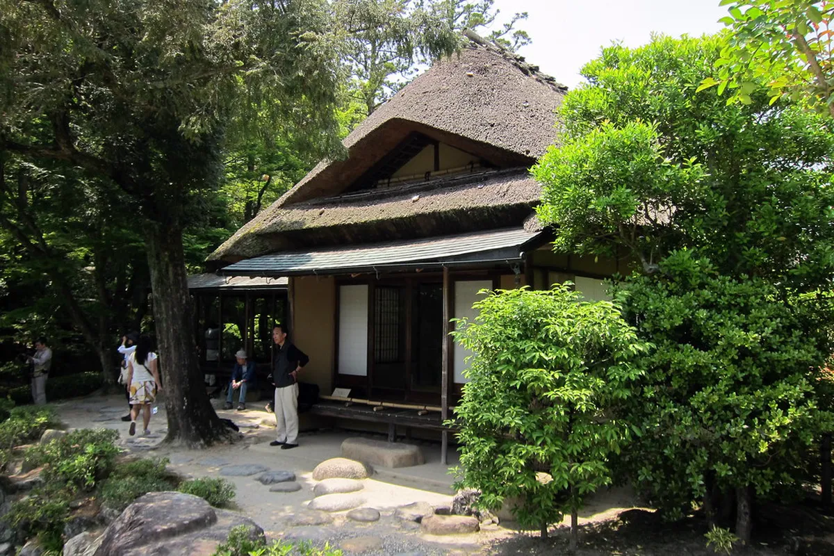 Traditional thatched-roof tea house at Isuien Garden in Nara with a view over the tranquil rear garden pond