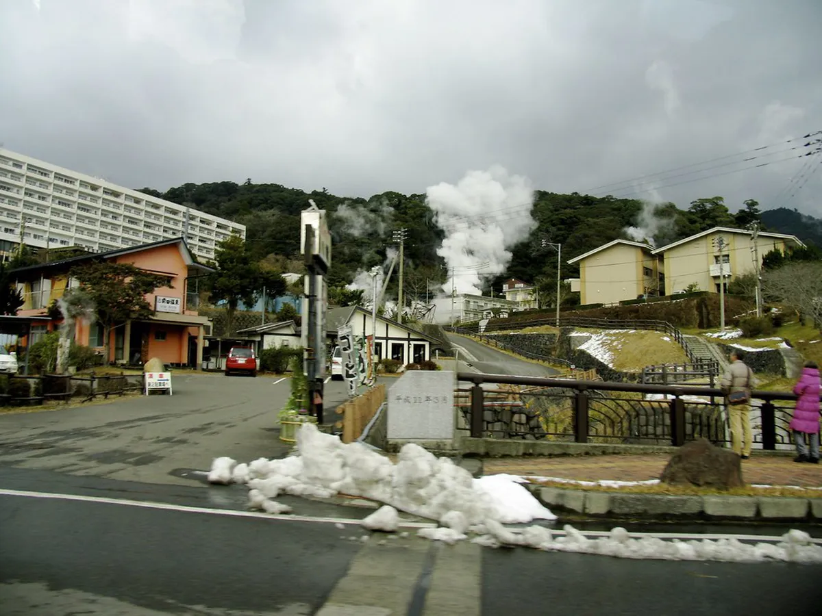 Outdoor onsen hot spring bath with steam rising and mountain scenery in Kagoshima Japan