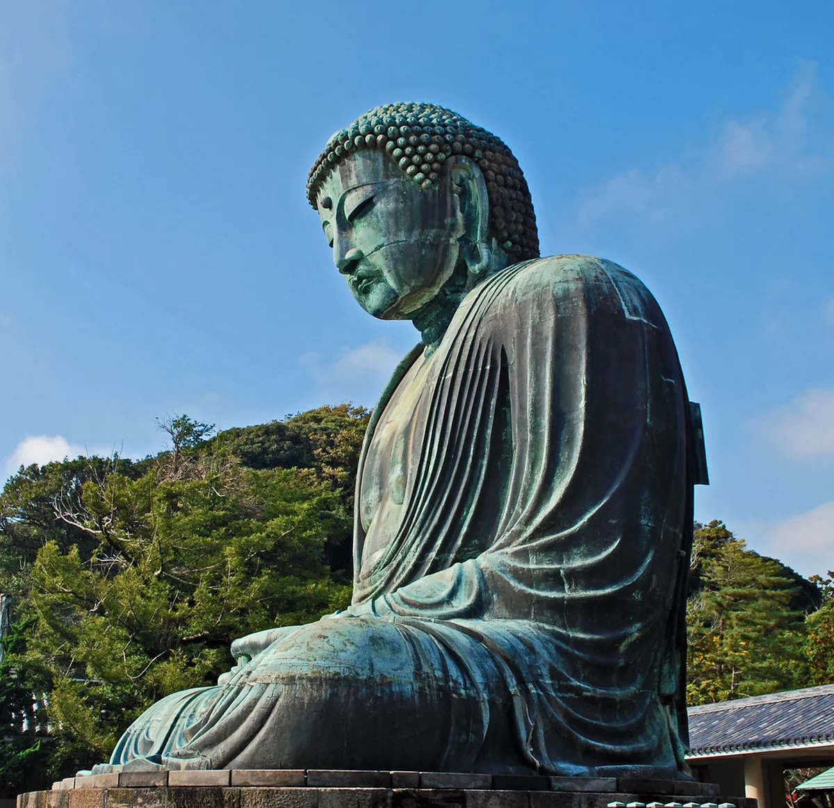 Kamakura Great Buddha bronze statue at Kotoku-in temple towering above visitors under a clear blue sky in Japan