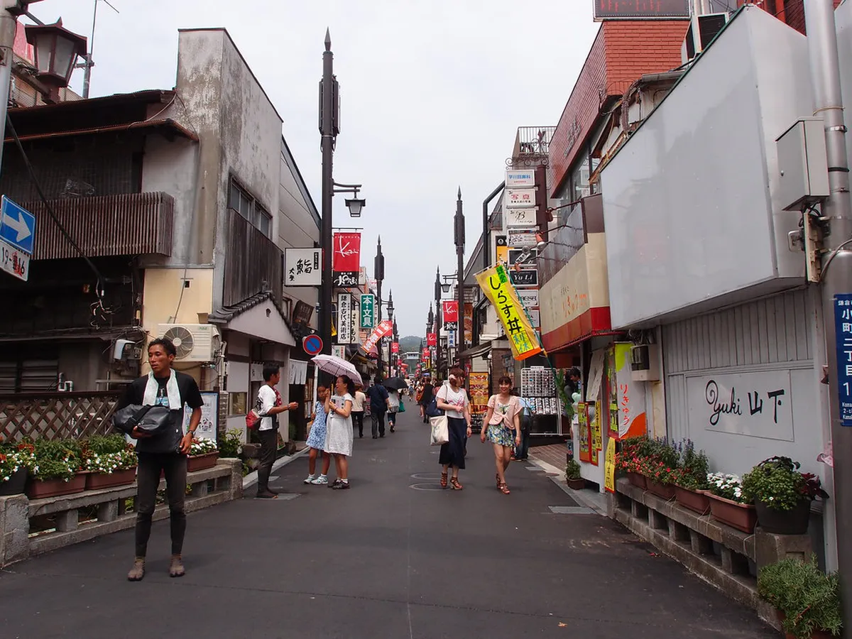 Komachi-dori shopping street in Kamakura Japan with food stalls and visitors browsing local snacks and souvenirs