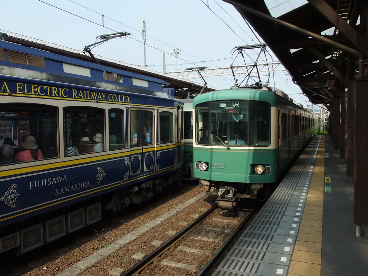 Enoden railway green train running along the scenic Kamakura Japan coastline with Sagami Bay in the background