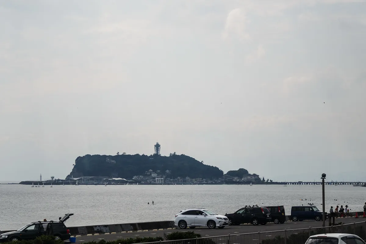 The vintage green Enoden electric railway tram running along the scenic Sagami Bay coastline near Kamakura, Japan