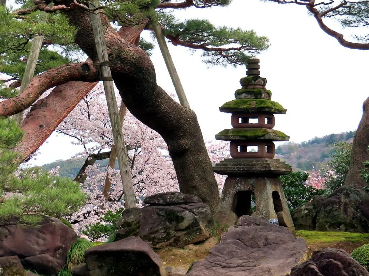 The iconic Kotoji stone lantern standing beside the tranquil pond inside Kenrokuen Garden in Kanazawa, Japan on a clear morning