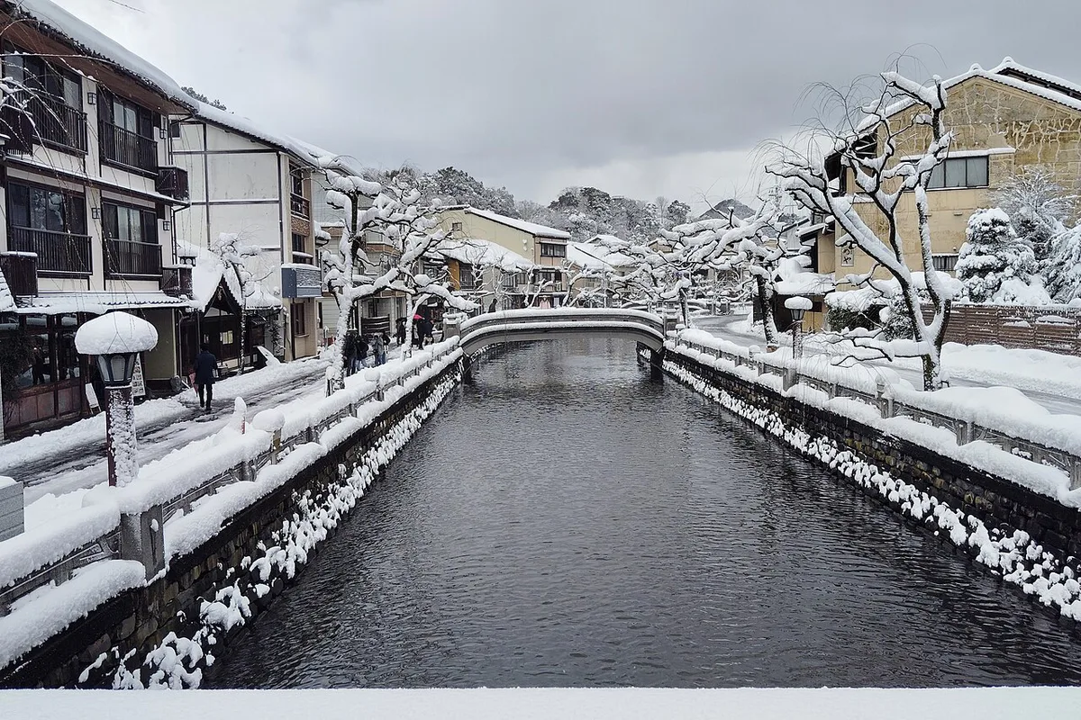 Visitors in yukata snacking along the Otani River street food stalls in Kinosaki Onsen, Japan — 1