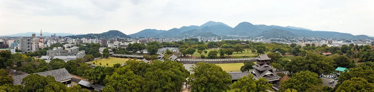 Wide view of Kumamoto Castle grounds with stone walls and turrets visible in Kumamoto, Japan