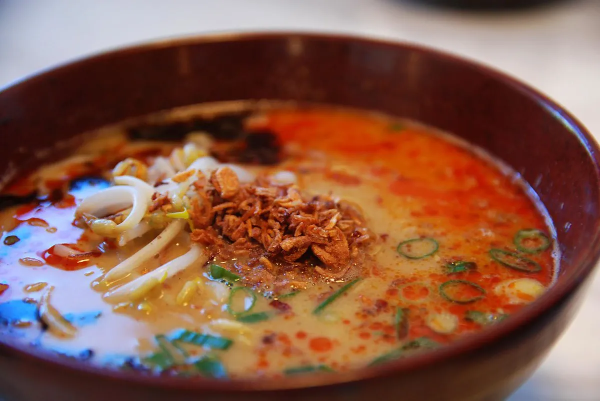 A steaming bowl of Kumamoto-style tonkotsu ramen with garlic chips and rich broth in Kumamoto, Japan