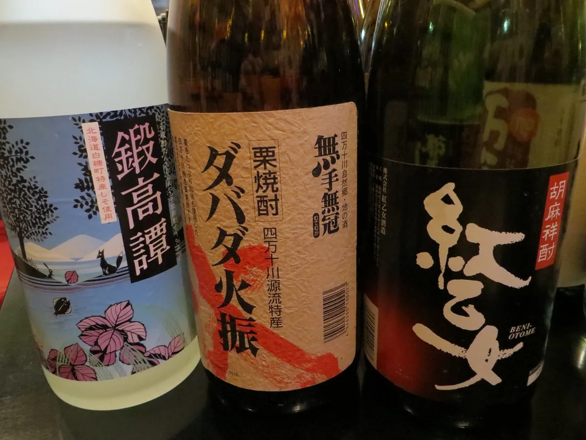Traditional Japanese bar counter with shochu bottles and glasses in a cozy Kyushu izakaya setting