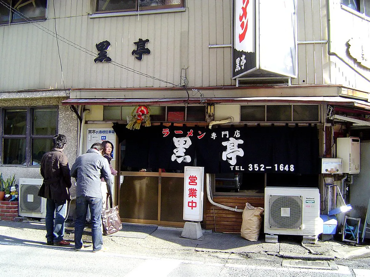 Traditional Japanese ramen shop exterior at night with lanterns and noren curtain hanging at the entrance in Japan