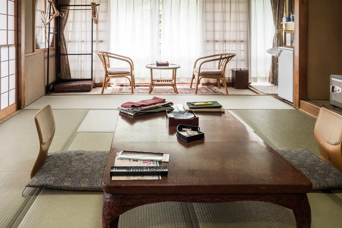 Traditional Japanese ryokan room with tatami mats, low table, and futon bedding set beside a private garden window