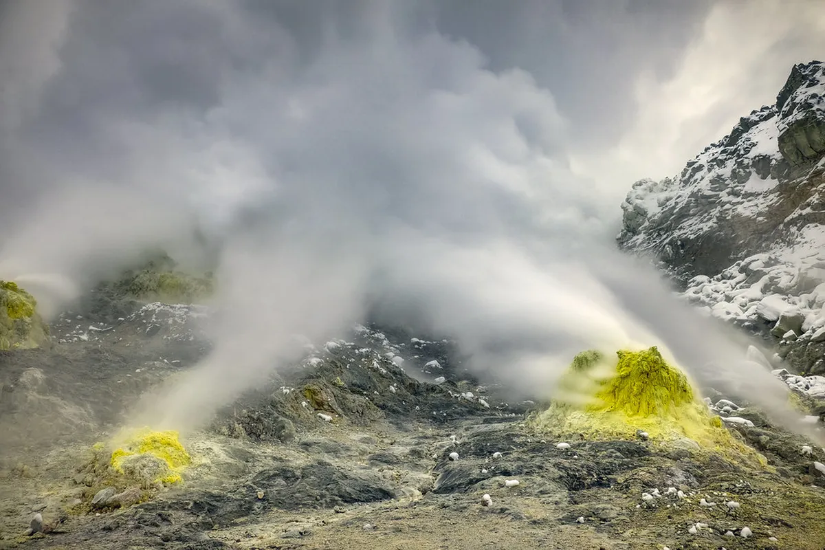 Mountain onsen steam vents rising from volcanic ground surrounded by forest and stone paths near Kurokawa, Japan