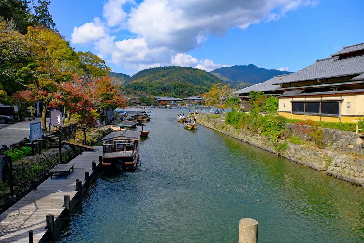 Serene Arashiyama river view framed by lush green bamboo forest and mountains in Kyoto, Japan