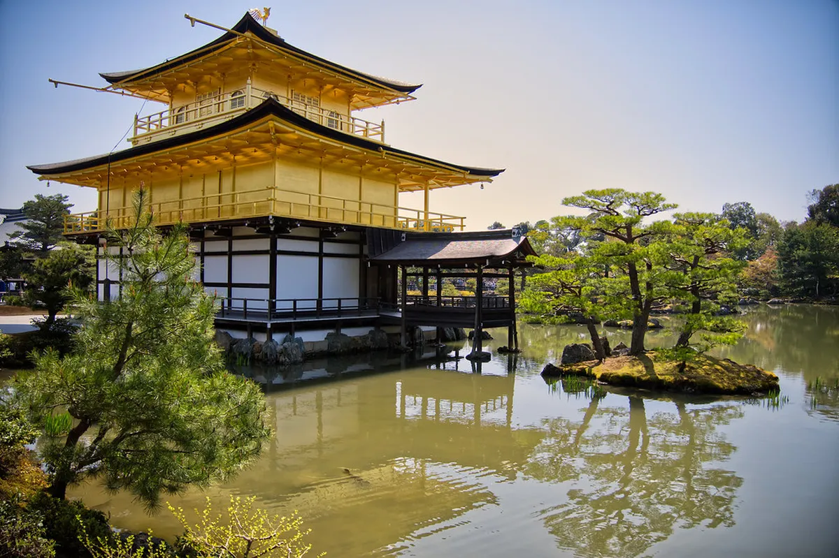 Kinkaku-ji Golden Pavilion covered in gold leaf reflecting perfectly in the still Mirror Pond in Kyoto, Japan