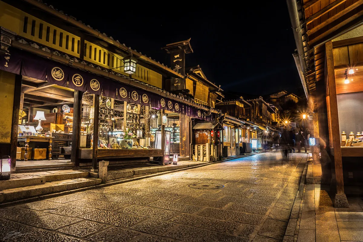 Narrow Pontocho alley at night lined with glowing izakaya bar signs along the Kamogawa River in Kyoto, Japan