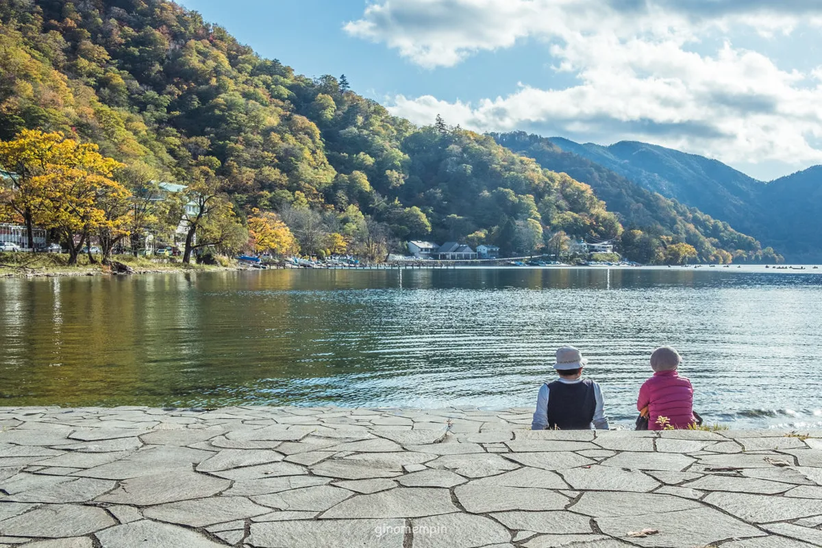 Lake Chuzenji shoreline with Mount Nantai reflected in calm alpine waters during autumn in Nikko, Japan