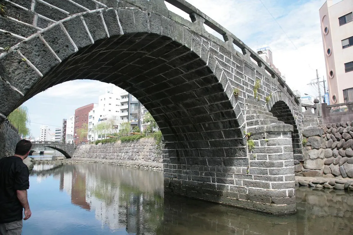 Historic Megane Bridge stone arch over the Nakashima River lined with traditional buildings in Nagasaki, Japan