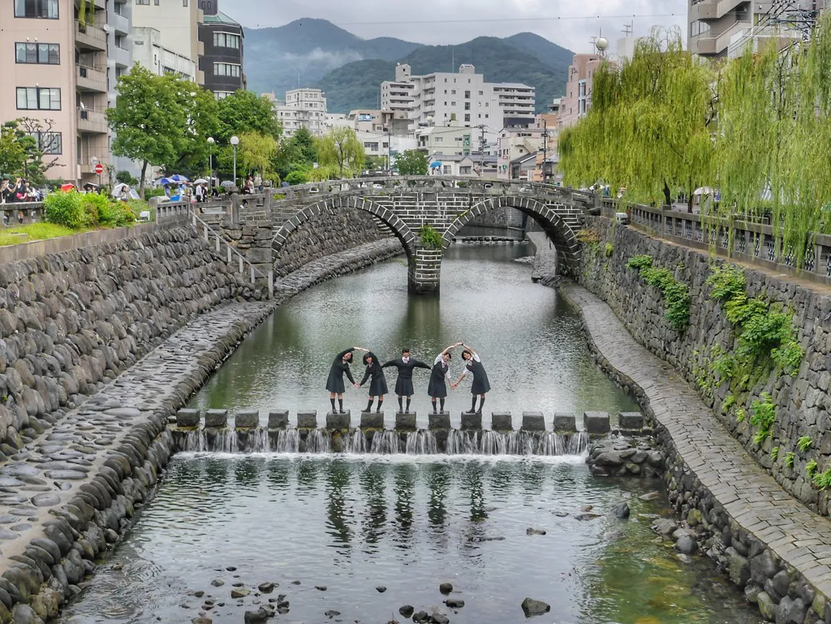 Spectacles reflection of Megane Bridge arches mirrored in the calm Nakashima River at Nagasaki, Japan