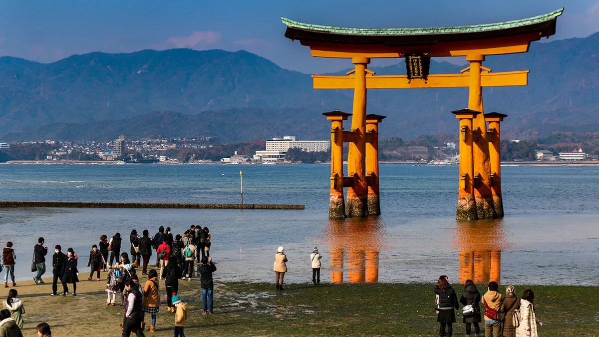 Great Torii Gate of Itsukushima Shrine standing in the sea at high tide with vermilion shrine corridors on Miyajima Island, Japan