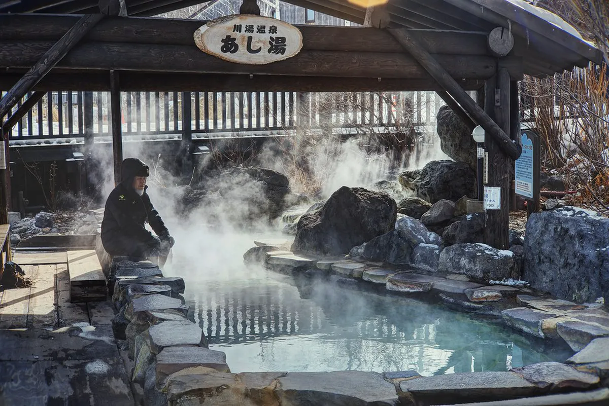 Traditional Japanese outdoor hot spring onsen bath surrounded by natural scenery in Japan