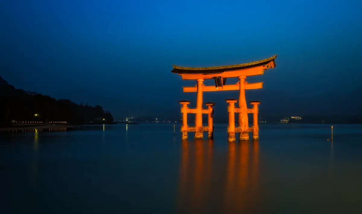 Miyajima island torii gate reflecting on the water at dusk, Japan