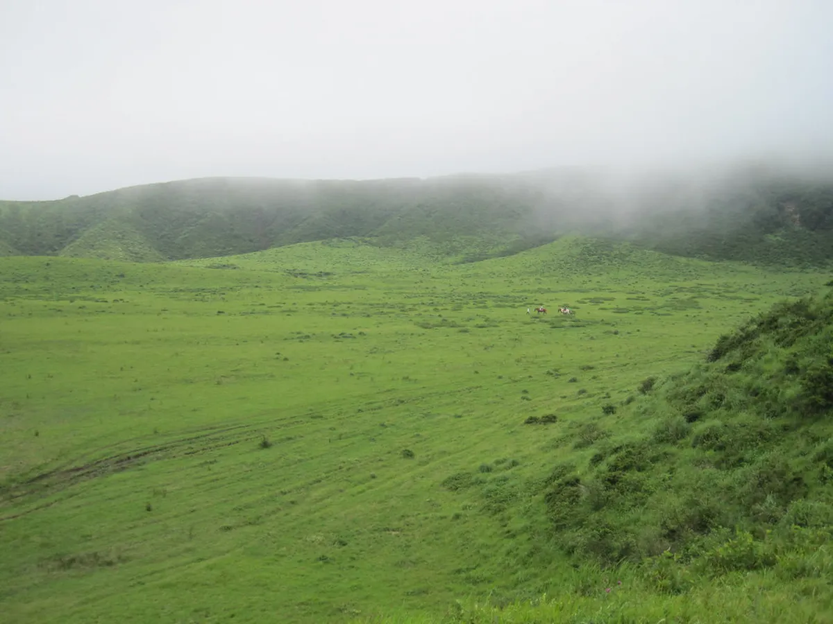 Kusasenri grasslands stretching across the Mount Aso caldera with volcanic peaks in the distance, Kumamoto, Japan