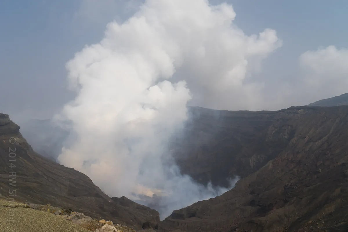 Nakadake crater of Mount Aso emitting steam and volcanic gases over the acidic turquoise lake in Kumamoto, Japan