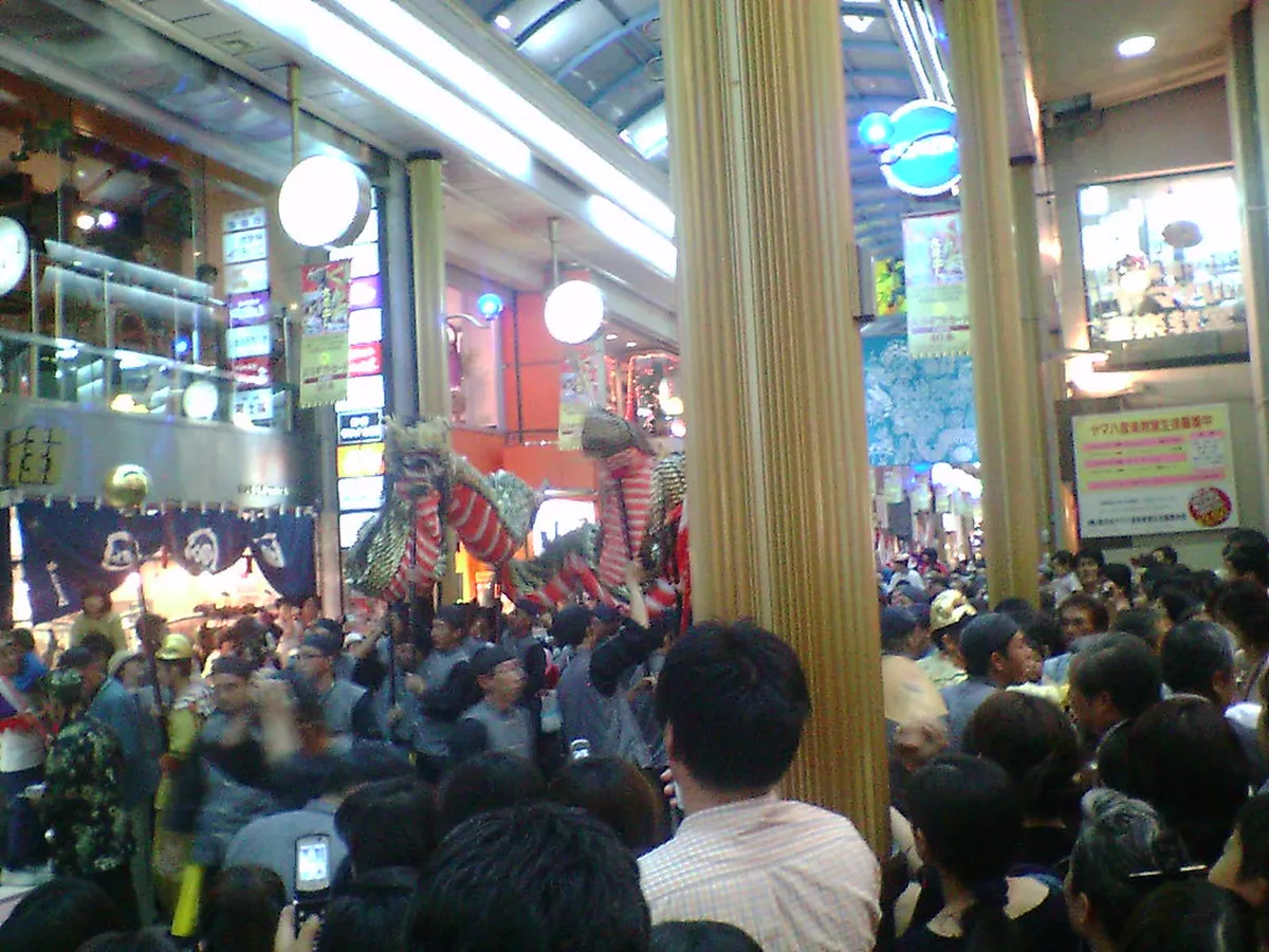 Large crowd gathered at a Nagasaki Kunchi festival performance venue watching the colorful float displays, Japan